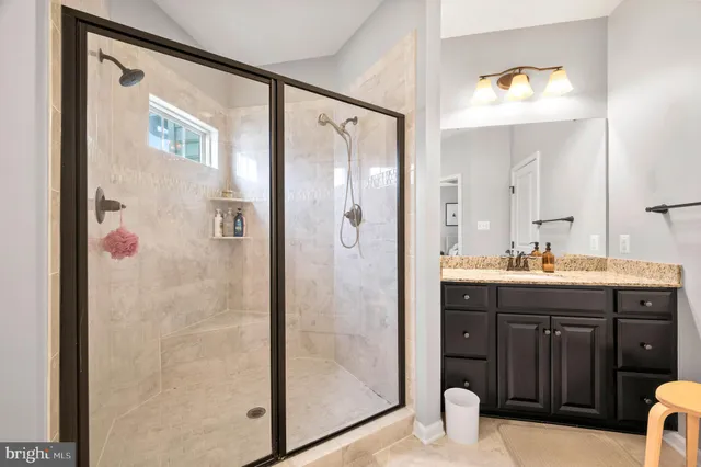 a view of a hallway with wooden floor and a bathroom
