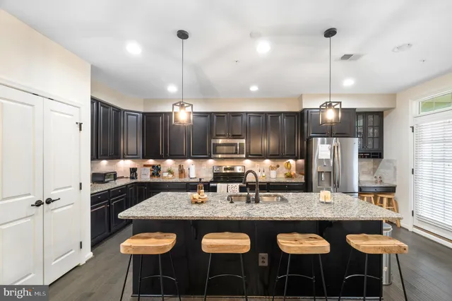 a kitchen with stainless steel appliances kitchen island granite countertop a refrigerator a stove a sink and a oven