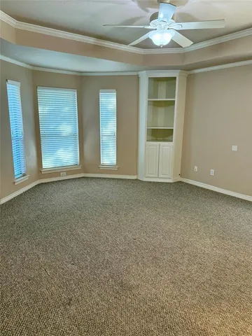 an empty room with chandelier fan and windows
