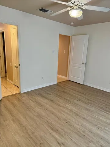 a view of a hallway with wooden floor and a bathroom