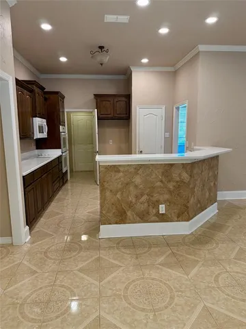 a view of a kitchen with kitchen island a counter top space appliances and a ceiling fan