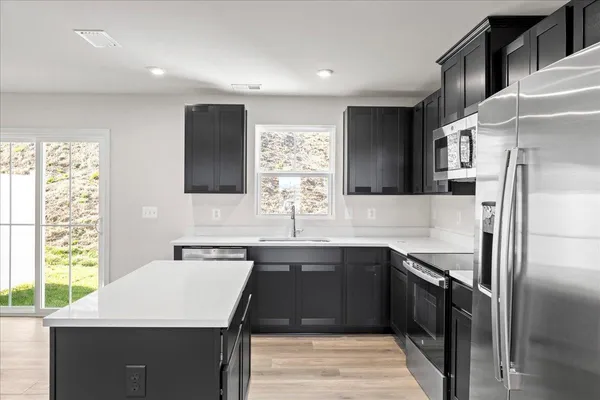 a kitchen with stainless steel appliances a refrigerator a sink a stove a microwave and island