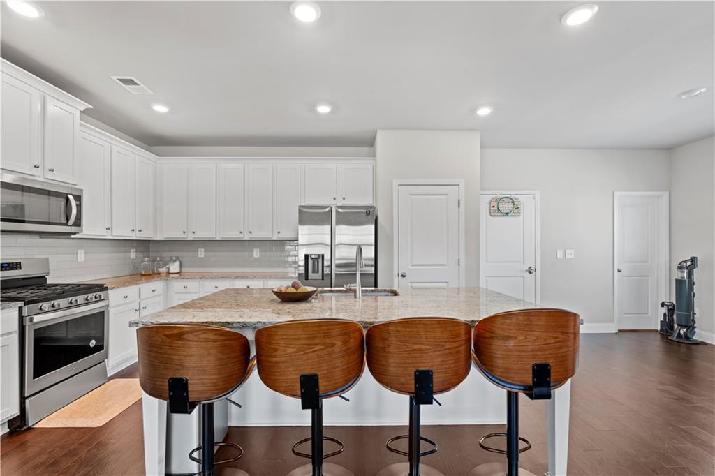 1030 Shy Lane Marietta, GA 30060 - Photo 13 of 50 a kitchen with stainless steel appliances granite countertop a stove a sink a refrigerator and white cabinets with wooden floor