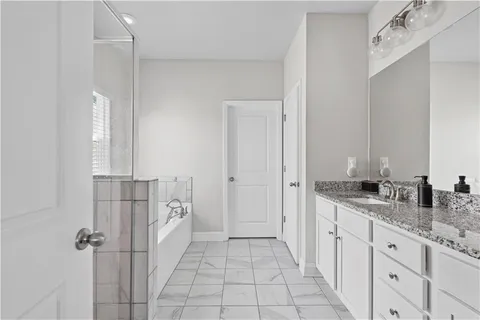 a spacious bathroom with a granite countertop sink a mirror and a shower