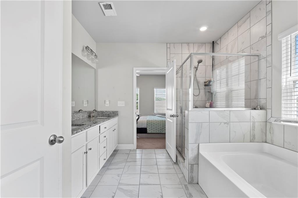 1030 Shy Lane Marietta, GA 30060 - Photo 30 of 50 a bathroom with a granite countertop sink a mirror a bathtub and shower