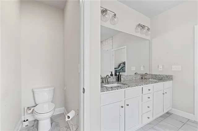 a bathroom with a granite countertop sink vanity mirror and toilet
