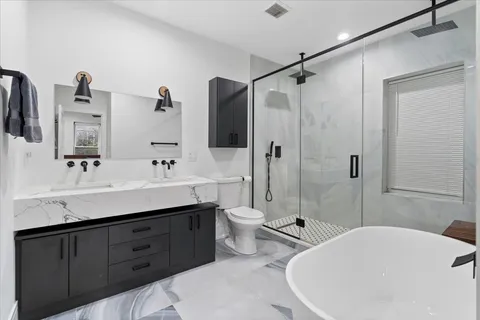 a bathroom with a double vanity sink toilet mirror and shower