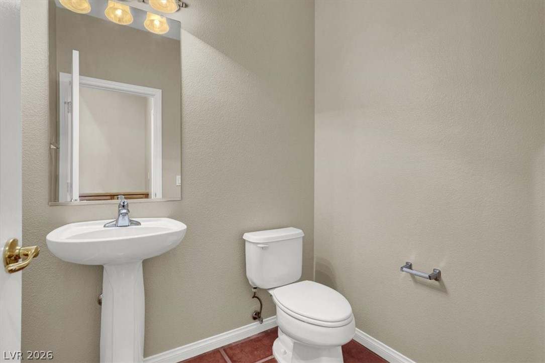 7308 Rustic Meadow Street Las Vegas, NV 89131 - Photo 22 of 27 A compact and functional powder room with a sleek pedestal sink and complementary tile flooring.