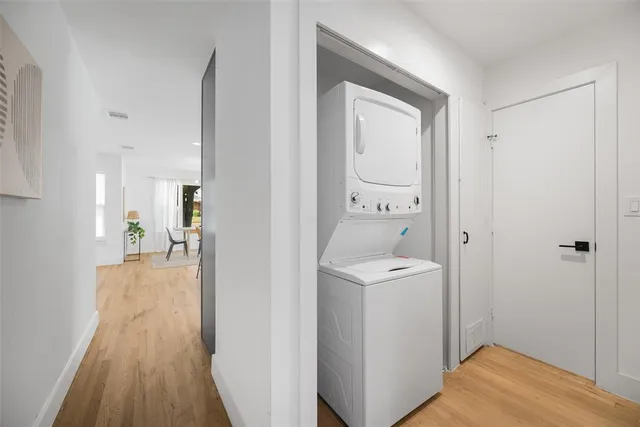 a view of a hallway with wooden floor and a bathroom