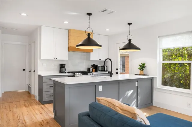 a kitchen with stainless steel appliances a sink a stove and a wooden floor