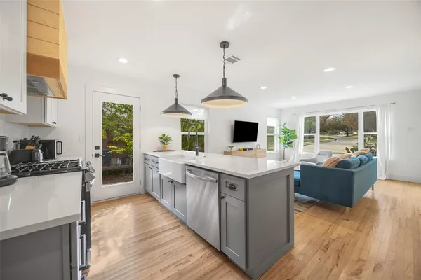a kitchen with stainless steel appliances kitchen island granite countertop a sink stove and wooden floor
