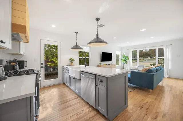 a kitchen with stainless steel appliances kitchen island granite countertop a sink stove and wooden floor