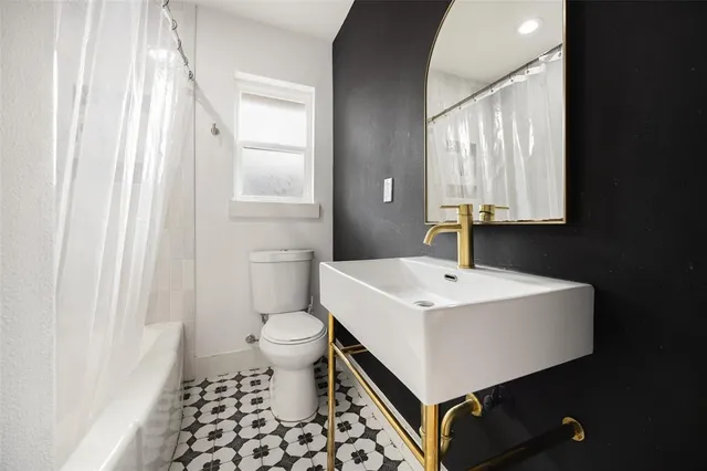 a bathroom with a sink a toilet a mirror and shower