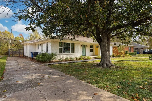 a white house that has a tree in front of a house