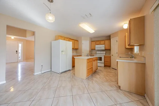 a kitchen with a refrigerator a stove top oven and white cabinets