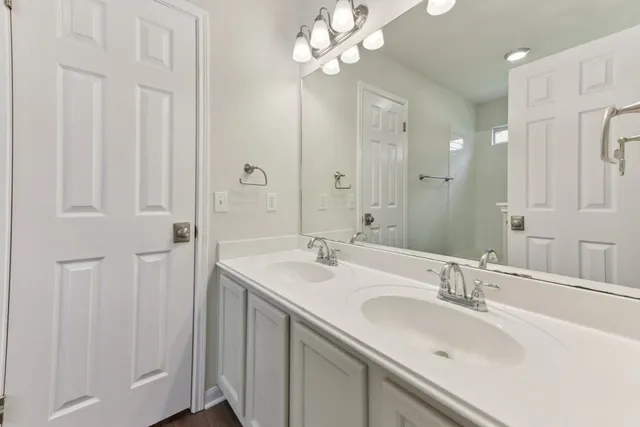 a bathroom with a double vanity sink a large mirror and shower