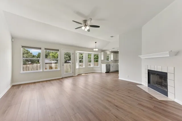 a view of an empty room with a window and wooden floor