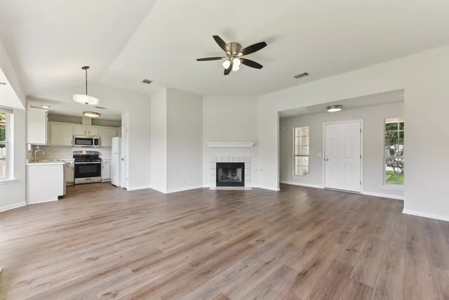 a view of a livingroom with a fireplace a ceiling fan and wooden floor