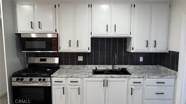 a kitchen with granite countertop white cabinets and appliances