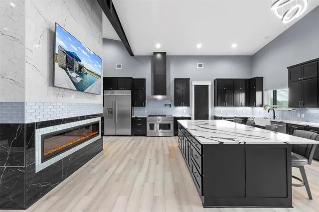 a large kitchen with stainless steel appliances kitchen island granite countertop a stove a sink dishwasher and a microwave oven with large wooden cabinets