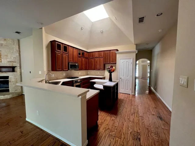 a kitchen with stainless steel appliances granite countertop a sink a stove and a wooden floors