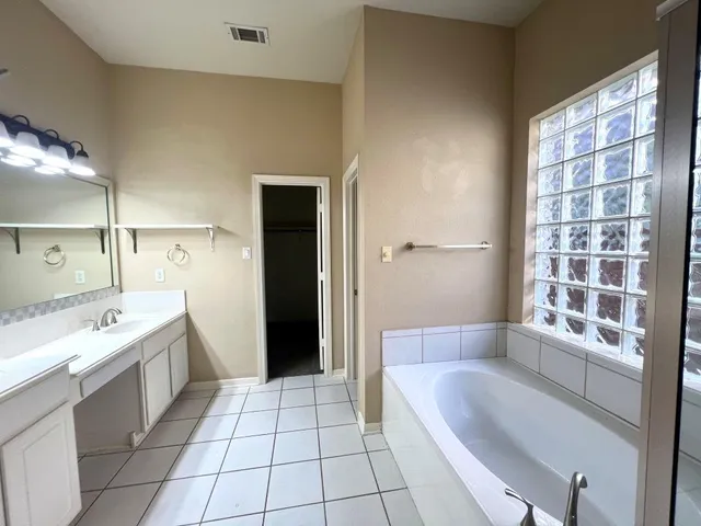 a spacious bathroom with a granite countertop tub a sink and a large mirror