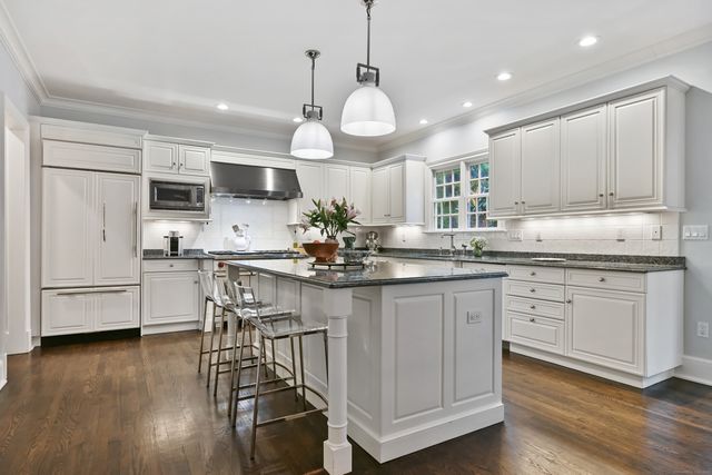 a kitchen with stainless steel appliances granite countertop a stove top oven a refrigerator a sink and cabinets with wooden floor