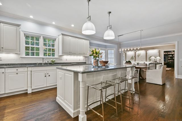a kitchen with stainless steel appliances granite countertop wooden floors and white cabinets