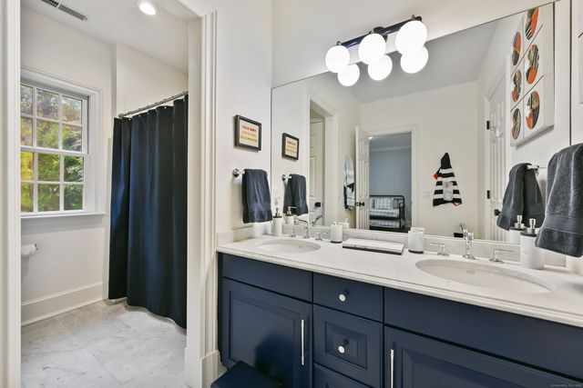 a bathroom with double vanity sinks a vanity a lamp and a mirror