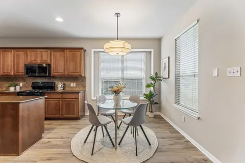 a kitchen with stainless steel appliances granite countertop a stove top oven a sink dishwasher a dining table and chairs with wooden floor