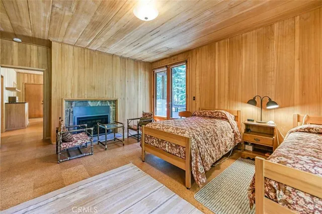 a spacious bedroom with a bed a table and chair with wooden floor