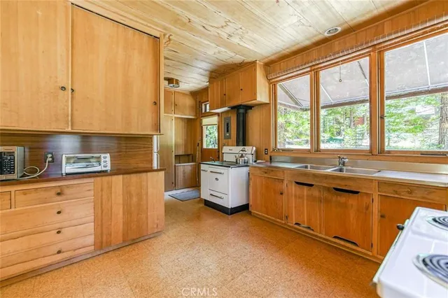 a kitchen with stainless steel appliances a sink cabinets and a large window