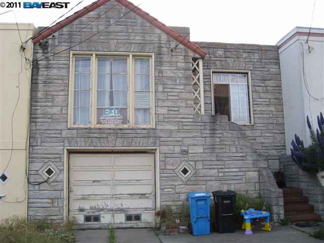 a front view of a building with brick wall and a large tree
