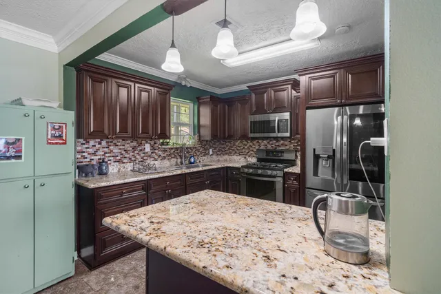 a kitchen with stainless steel appliances kitchen island granite countertop a sink refrigerator and cabinets