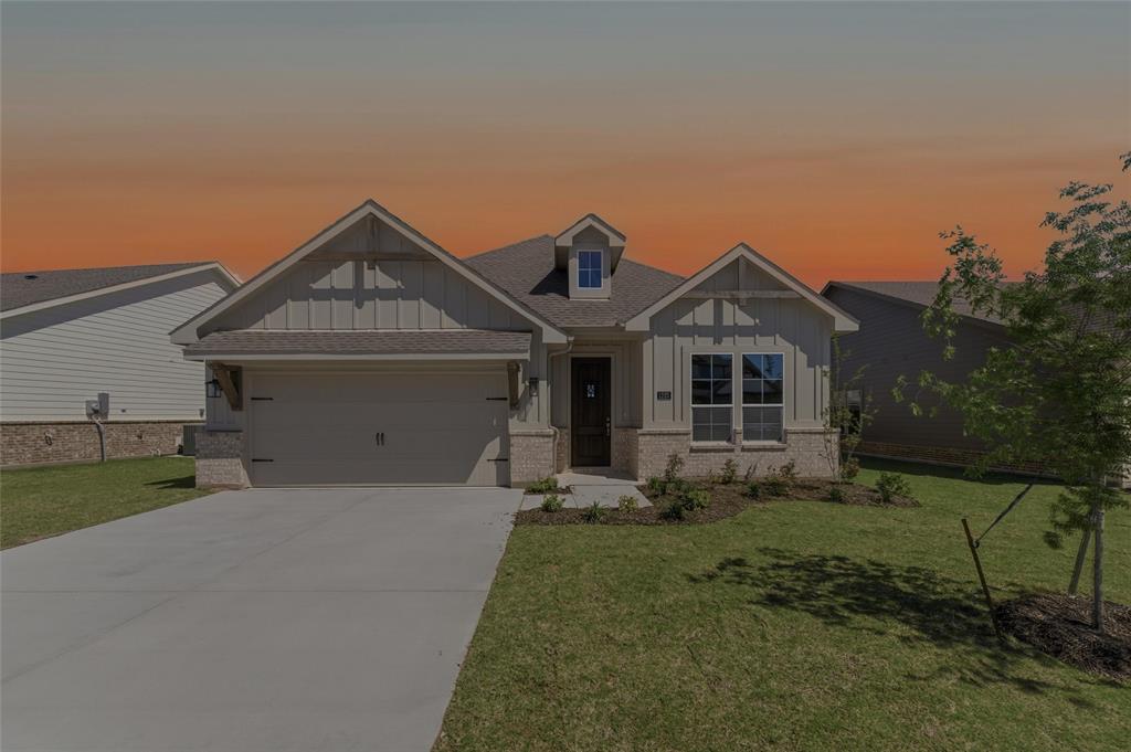 Craftsman house with board and batten siding, brick siding, a front yard, and an attached garage