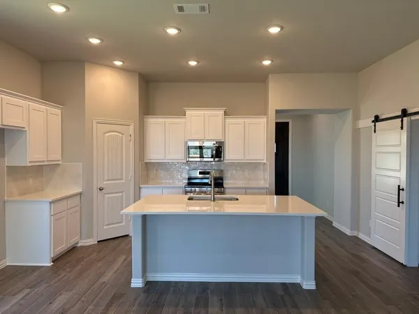 a large kitchen with stainless steel appliances a large counter top and a refrigerator