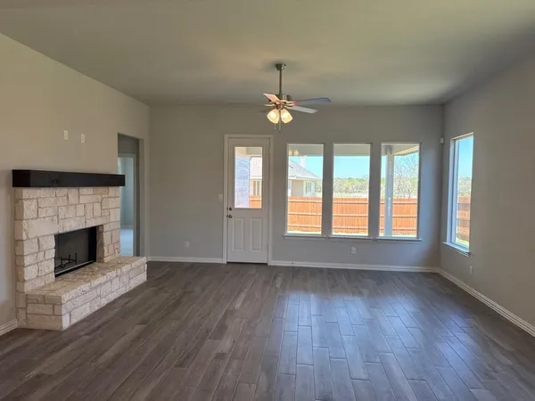 an empty room with wooden floor fireplace and windows