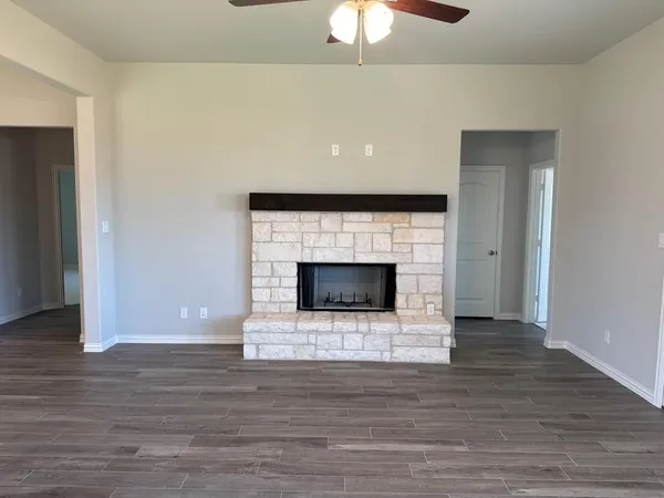 a view of an empty room with wooden floor and a fireplace