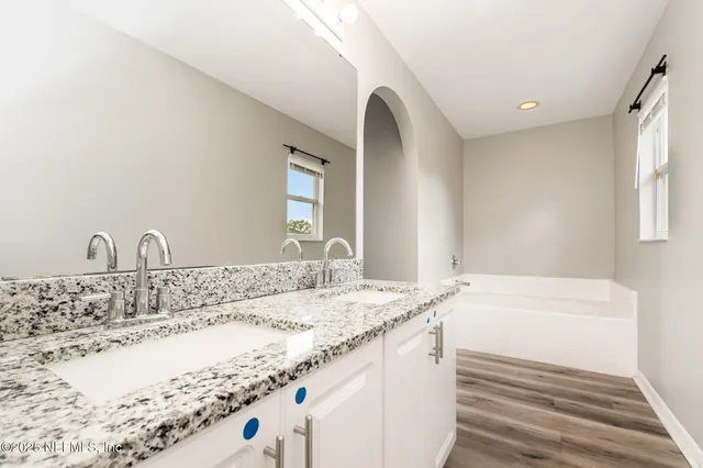 a bathroom with a granite countertop sink and a bathtub