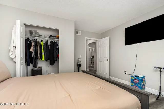 a bedroom with a bed and a flat tv screen on wall