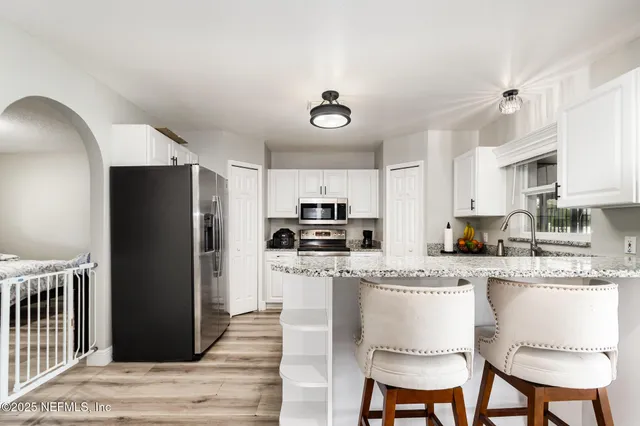 a kitchen with stainless steel appliances granite countertop a refrigerator a stove a sink dishwasher and a refrigerator with wooden floor