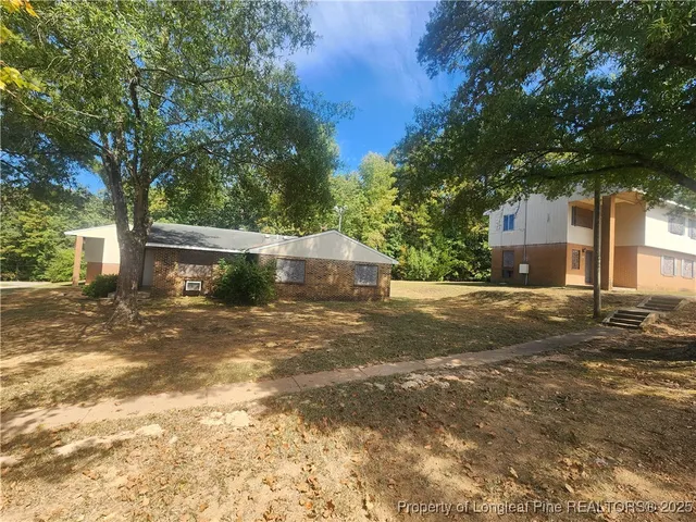 a view of a house with a yard and large tree