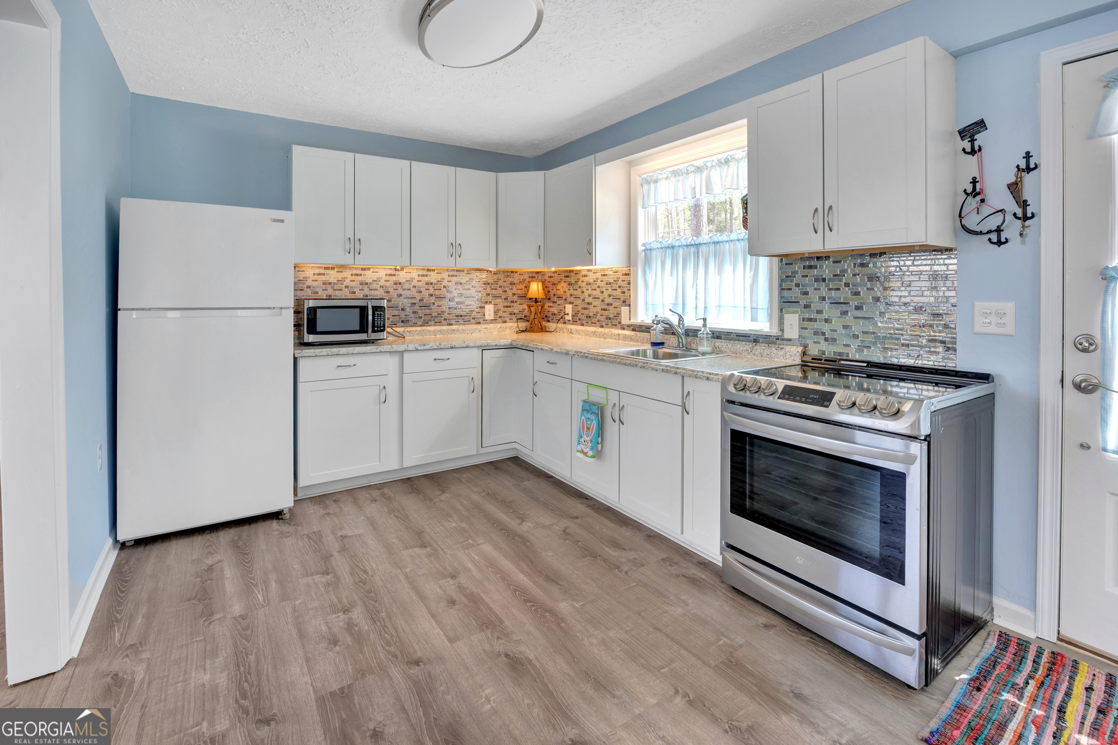 411 Alcovy Road Mansfield, GA 30055 - Photo 20 of 49 a kitchen with cabinets appliances wooden floor and a window