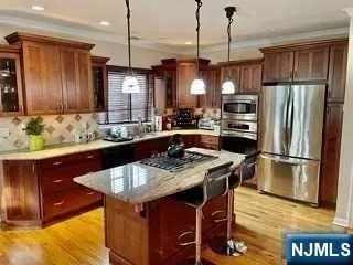 a kitchen with stainless steel appliances granite countertop a sink a stove a refrigerator and cabinets