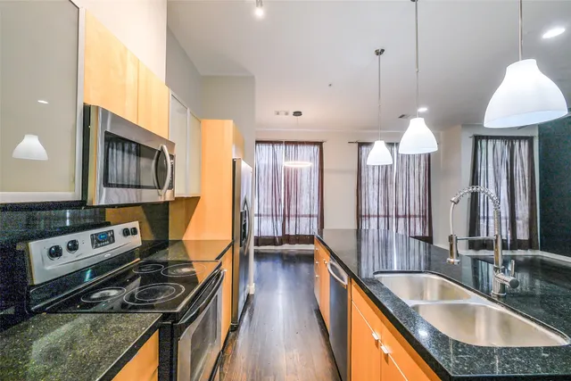 a kitchen with stainless steel appliances granite countertop a stove a sink and a wooden floors