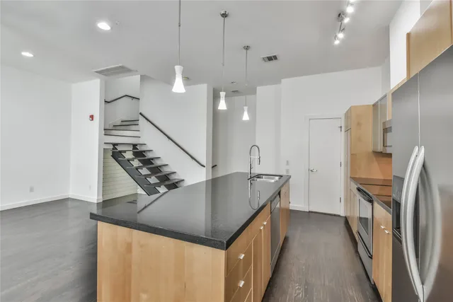 a kitchen with stainless steel appliances granite countertop a refrigerator a sink and a stove