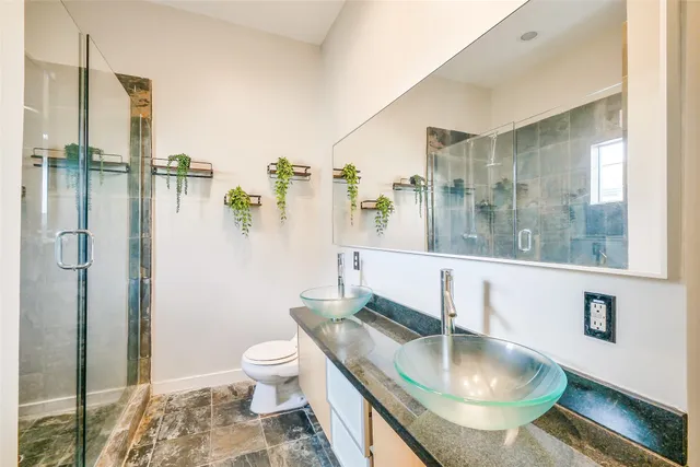 a bathroom with a granite countertop sink a toilet a mirror and shower