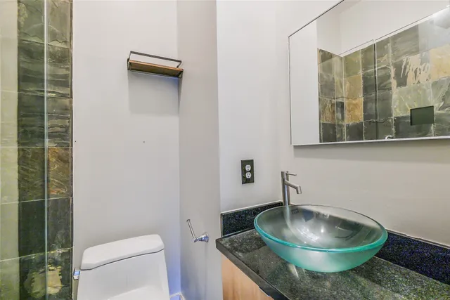 a bathroom with a granite countertop toilet and a sink