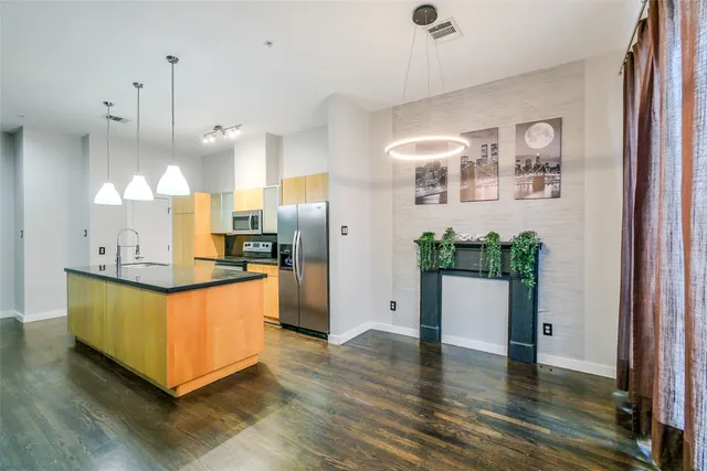 a kitchen with stainless steel appliances granite countertop a refrigerator a sink a stove and a wooden floors