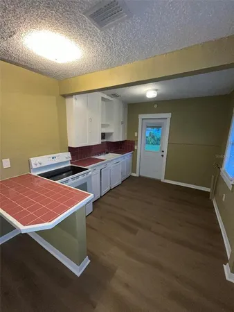 a large white kitchen with wooden floor and stainless steel appliances